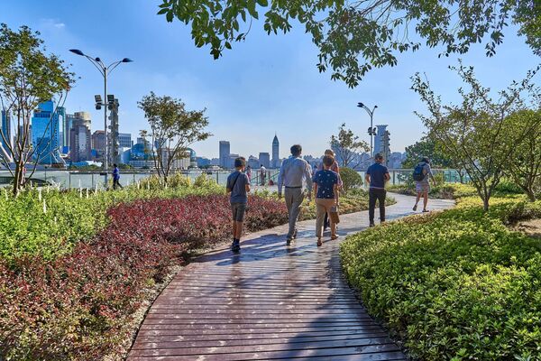 Person walking along a riverside path in a city